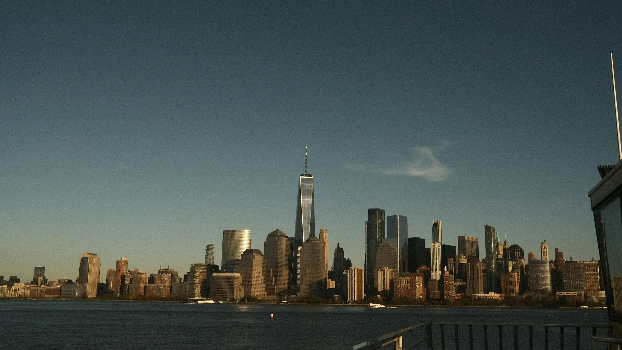 Lower Manhattan skyline and One World Trade Center at dusk, seen across the Hudson River